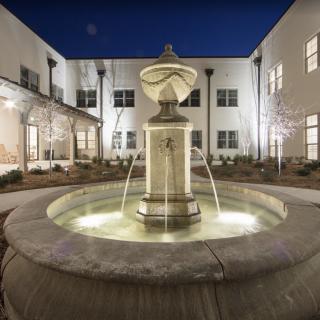 A beautifully lit fountain in the courtyard of a modern building at night.