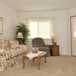 A cozy living room with a floral sofa, armchair, coffee table, and window.
