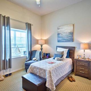 A cozy bedroom featuring a single bed, side table with a lamp, and a comfortable chair by the window.
