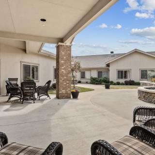 Spacious patio with comfortable outdoor seating and a fire pit under a partly cloudy sky.