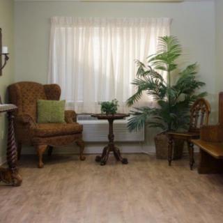 A cozy living room with an armchair, small table, and a potted plant by the window.