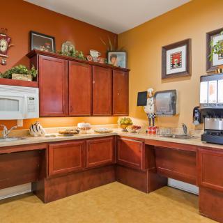 A cozy kitchen area with wooden cabinets, a microwave, and coffee maker, adorned with wall decor and framed pictures.