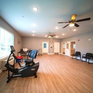 A spacious exercise room with a stationary bike and seating area.