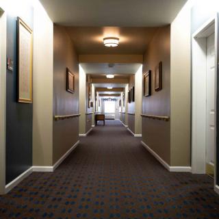 A long, empty hallway with carpeting and warm lighting.