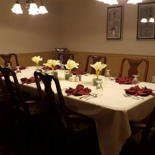A warmly lit dining room with a beautifully set table, adorned with flowers and elegant decor.