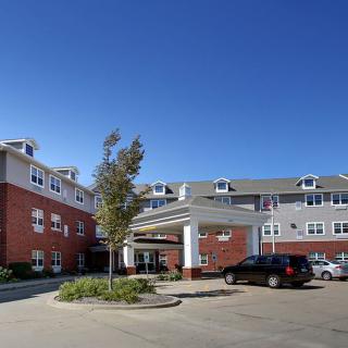 A hotel with a car parked in front of its entrance under a clear blue sky.