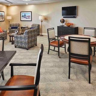 A comfortable lounge area with chairs, tables, and a television.