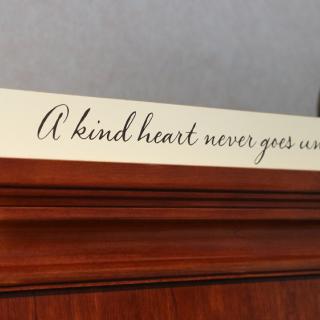 A decorative wall sign displaying the quote 'A kind heart never goes unwelcome.'