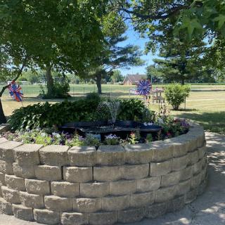 A serene garden featuring a small fountain and vibrant flowers surrounded by lush greenery.