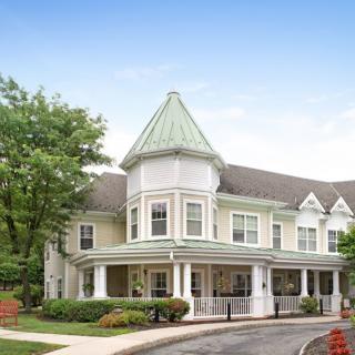 A Victorian-style house with a prominent turret and surrounding greenery.