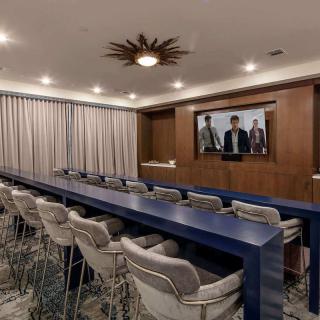 A modern conference room with rows of seating and a large presentation screen on the wall.