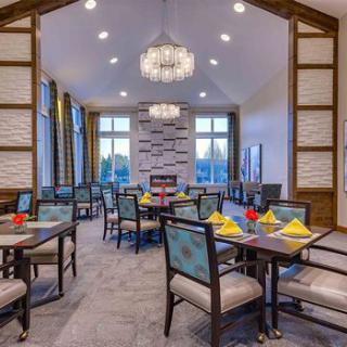 A modern restaurant dining area with elegant chandeliers and neatly arranged tables and chairs.