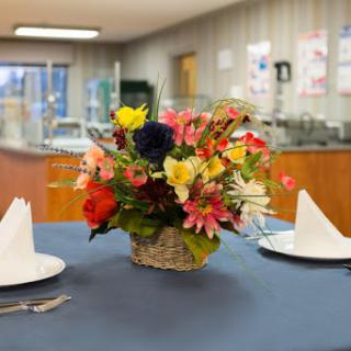 A beautifully arranged floral centerpiece on a dining table, accompanied by neatly folded napkins and cutlery.