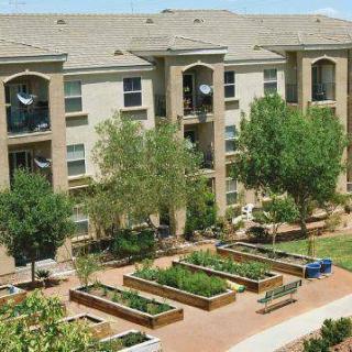 Apartment complex with a community garden and landscaped outdoor area.