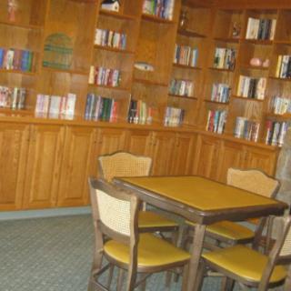 A cozy library corner with wooden shelves filled with books and a table surrounded by chairs.
