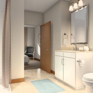 A modern bathroom with a sink, mirror, and toilet, featuring soft lighting and a light blue bath mat.