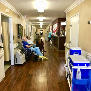 A serene hallway scene in a nursing home with residents and staff.
