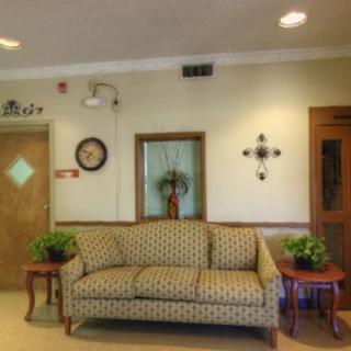 A cozy lobby area featuring a patterned sofa, decorative plants, and wall art.