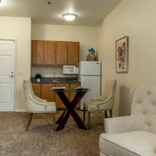 A cozy kitchenette and dining area in an apartment, featuring modern chairs, a table, and essential kitchen appliances.