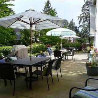 A serene outdoor patio with tables, chairs, and umbrellas set amidst a garden backdrop.