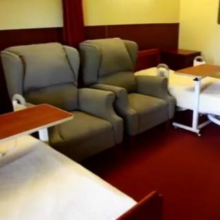 A hospital room with comfortable chairs and medical beds arranged for patient care.
