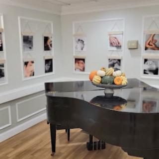 A stylish interior featuring a grand piano and artistic photographs on the walls.