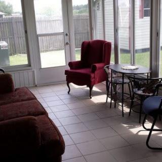 A cozy sunroom with comfortable seating and large windows.
