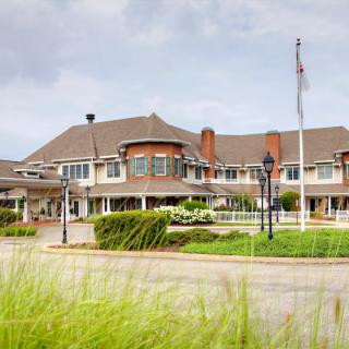 A large multi-story building with well-maintained landscaping and an American flag in front.