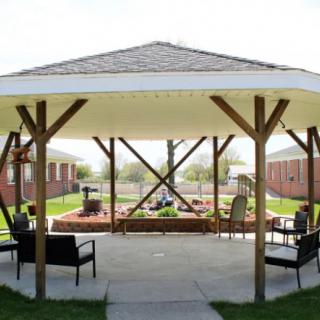 An outdoor gazebo with seating and a garden area.
