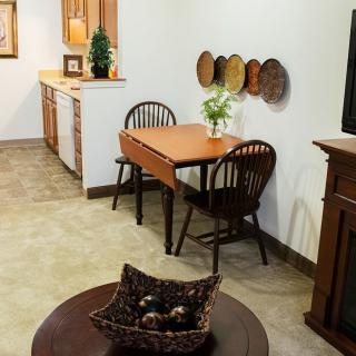 A cozy dining area with a wooden table and chairs, decorated with wall plates and a vase centerpiece.