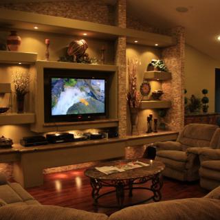 A cozy living room with a home theater setup, featuring recliners and decorative shelves.