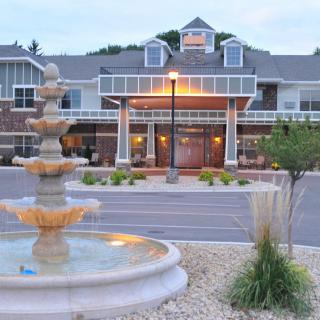 A scenic view of a building entrance with a multi-tiered fountain in the foreground during the evening.