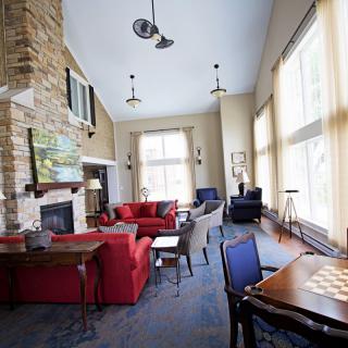 A modern living room featuring large windows, a stone fireplace, and comfortable seating with red and blue sofas.