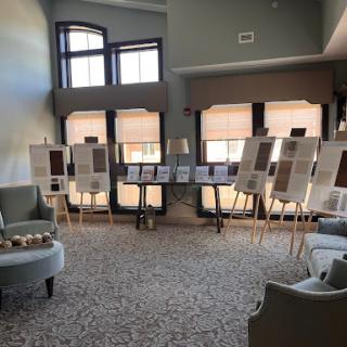 A spacious interior featuring an art exhibition with several display boards, surrounded by comfortable seating.