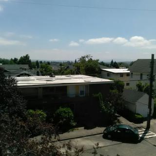 A sunny view of a residential neighborhood with houses, trees, and parked cars.