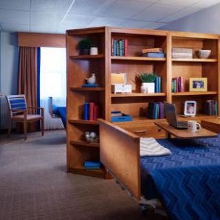 A cozy bedroom with a wooden bookshelf dividing the space.