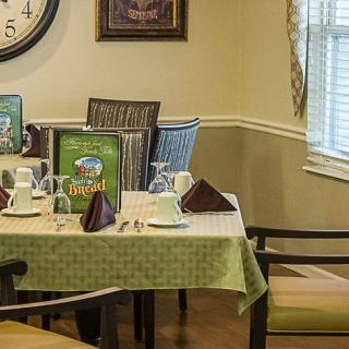 A neatly set dining table with a green tablecloth in a cozy restaurant setting.