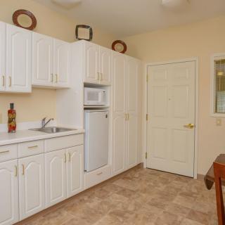 A small, neatly organized kitchen with white cabinets and a tiled floor.