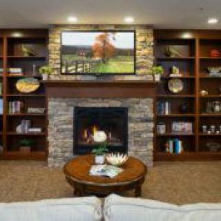 A cozy living room with a stone fireplace, built-in bookshelves, and a wall-mounted television.