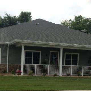 A single-story residential house with a front porch and well-maintained lawn.