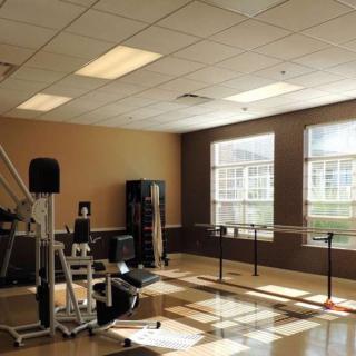 A well-lit gym with various fitness equipment and large windows.