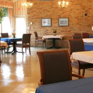 A cozy restaurant dining area with neatly arranged tables and chairs, featuring a brick wall and warm lighting.