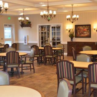A well-lit dining room with neatly arranged tables and chairs.