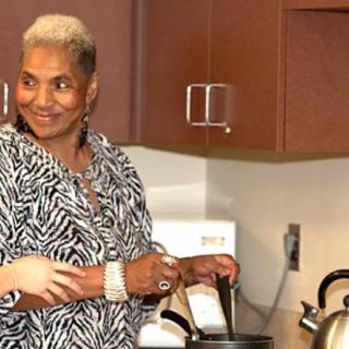 A woman is smiling while cooking in the kitchen.