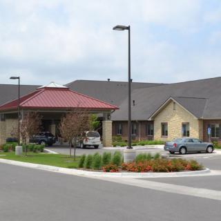 A nursing home building with a landscaped entrance and parking area.