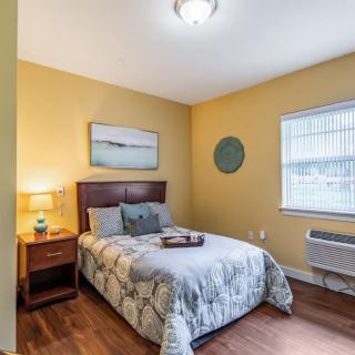 A cozy bedroom with yellow walls, featuring a comfortable bed and nightstand.