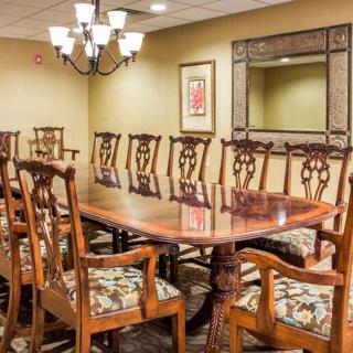 A well-furnished dining room with an elegant wooden table and matching chairs, adorned by a chandelier.