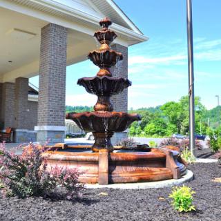 A beautifully designed four-tiered fountain surrounded by lush landscaping.