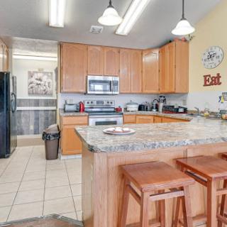 A modern kitchen featuring wooden cabinets and a granite countertop, equipped with essential appliances.