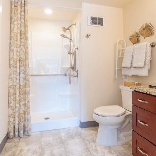A clean and modern bathroom with a shower, toilet, and neatly arranged towels.